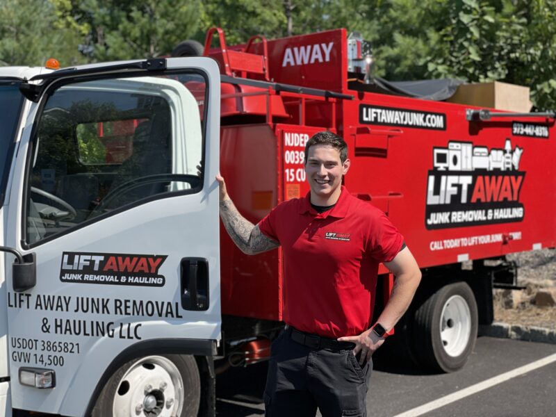 Junk removal professional smiling next to a truck during junk removal services in Sussex County, NJ